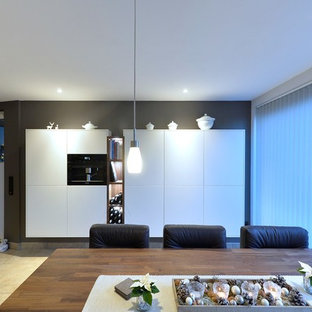 ドルトムントの中サイズのコンテンポラリースタイルのLDKの画像 (黒い壁、セラミックタイルの床、暖炉なし、ベージュの床)