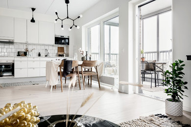 This is an example of a mid-sized modern open concept living room in Gothenburg with white walls and light hardwood floors.