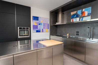 Foto di una grande cucina contemporanea con lavello integrato, ante lisce, ante in acciaio inossidabile, top in acciaio inossidabile, pavimento in cemento e pavimento grigio