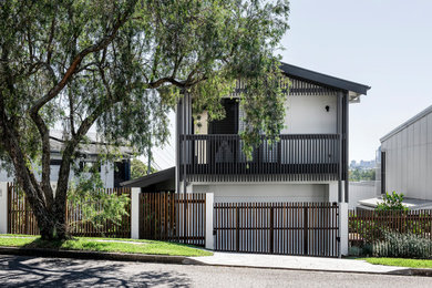 This is an example of a large contemporary split-level white house exterior in Brisbane with metal siding, a gable roof and a metal roof.