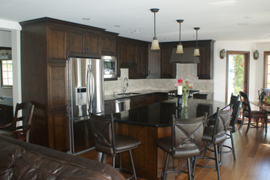 Enclosed kitchen - transitional u-shaped enclosed kitchen idea in Ottawa with a double-bowl sink, raised-panel cabinets, dark wood cabinets, granite countertops, beige backsplash, cement tile backsplash, stainless steel appliances and an island