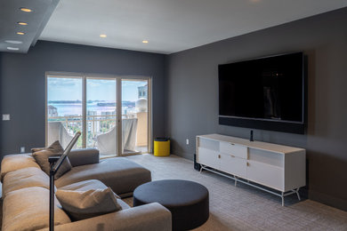 Imagen de sala de estar tipo loft moderna de tamaño medio con paredes grises, moqueta, televisor colgado en la pared, suelo gris y bandeja