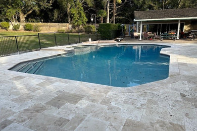 Imagen de piscina natural contemporánea grande en patio trasero con adoquines de piedra natural