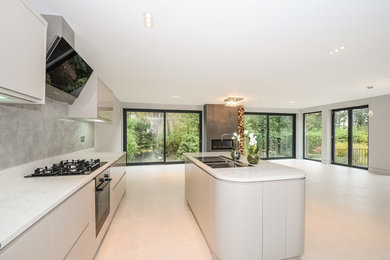 Example of a minimalist kitchen design in Berkshire with a drop-in sink, marble countertops, gray backsplash and paneled appliances