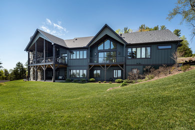 Example of a large arts and crafts green two-story board and batten exterior home design in Other with a shingle roof and a black roof