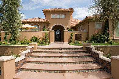 Example of a large tuscan brown two-story stucco house exterior design in Other with a hip roof and a tile roof