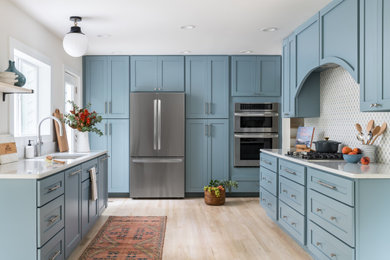 アトランタにあるラグジュアリーな中くらいなトランジショナルスタイルのおしゃれなキッチン (アンダーカウンターシンク、シェーカースタイル扉のキャビネット、青いキャビネット、珪岩カウンター、青いキッチンパネル、セラミックタイルのキッチンパネル、シルバーの調理設備、淡色無垢フローリング、アイランドなし、マルチカラーの床、白いキッチンカウンター) の写真