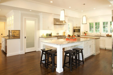Inspiration for a large transitional u-shaped eat-in kitchen in New York with an undermount sink, shaker cabinets, white cabinets, glass benchtops, white splashback, porcelain splashback, stainless steel appliances, medium hardwood floors, multiple islands and brown floor.