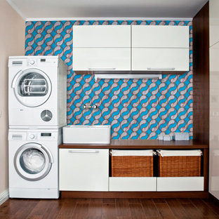 This is an example of a medium sized modern u-shaped separated utility room in Gold Coast - Tweed with a single-bowl sink, wood worktops, brown cabinets, blue walls, plywood flooring, a stacked washer and dryer, brown floors, brown worktops and beaded cabinets.