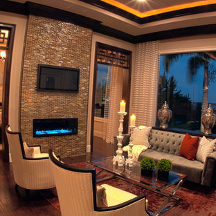 Diseño de salón para visitas abierto, mediterráneo, con paredes beige, suelo de madera en tonos medios, chimeneas suspendidas, marco de chimenea de baldosas y/o azulejos y televisor colgado en la pared