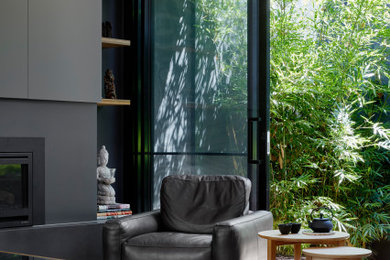 Design ideas for a mid-sized modern open concept living room in Melbourne with black walls, medium hardwood floors, a standard fireplace, a plaster fireplace surround and a built-in media wall.