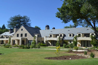 Example of a huge gray three-story stone house exterior design in Other with a gray roof