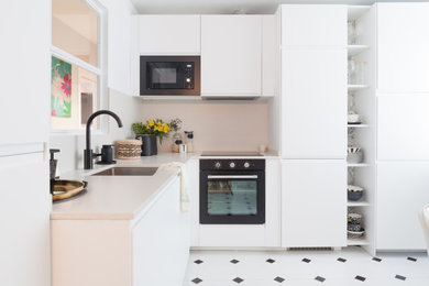Diseño de cocinas en L clásica renovada de tamaño medio abierta sin isla con fregadero bajoencimera, armarios con paneles lisos, puertas de armario blancas, encimera de cuarzo compacto, salpicadero beige, puertas de cuarzo sintético, electrodomésticos negros, suelo de baldosas de cerámica, suelo blanco y encimeras beige