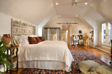 Example of an eclectic master medium tone wood floor bedroom design in Raleigh with beige walls