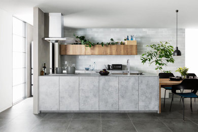 Foto di una cucina minimalista con lavello sottopiano, ante a filo, ante grigie, top in laminato, paraspruzzi grigio, penisola, pavimento grigio e top grigio