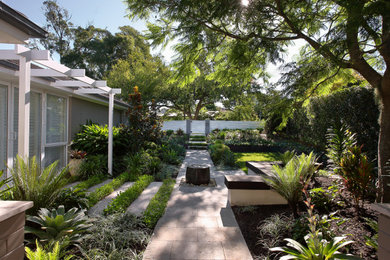 This is an example of a mid-sized contemporary front yard partial sun garden in Sydney with a garden path, natural stone pavers and a metal fence.