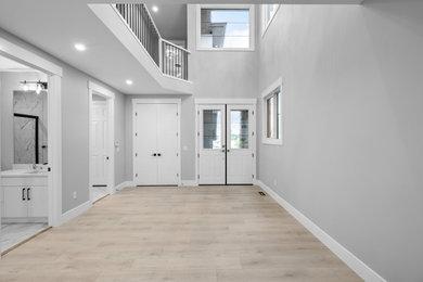 Inspiration for a contemporary painted wood floor entryway remodel in Calgary with gray walls and a white front door