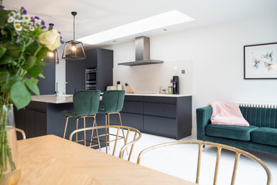 Large scandi single-wall kitchen/diner in London with a built-in sink, flat-panel cabinets, black cabinets, engineered stone countertops, white splashback, stone slab splashback, integrated appliances, ceramic flooring, an island, white floors and white worktops.