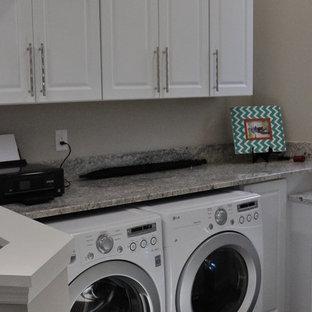 マイアミの小さいトラディショナルスタイルのおしゃれなランドリークローゼット (レイズドパネル扉のキャビネット、黄色いキャビネット、御影石カウンター、グレーの壁、無垢フローリング、左右配置の洗濯機・乾燥機、茶色い床、グレーのキッチンカウンター) の写真