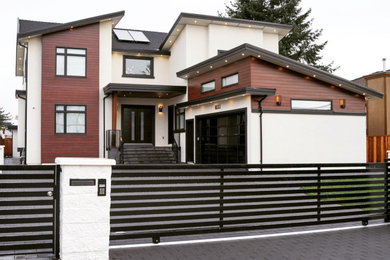Large trendy three-story stucco house exterior photo in Vancouver with a shingle roof