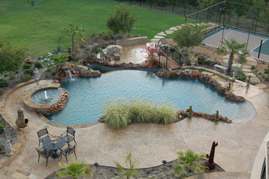 Large mountain style backyard custom-shaped and stamped concrete hot tub photo in Dallas
