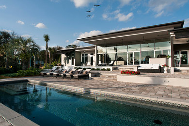 Inspiration for a large contemporary backyard brick patio kitchen remodel in Orlando with a roof extension