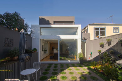 Cette photo montre une petite façade de maison métallique et blanche moderne à un étage avec un toit plat, un toit en métal et un toit gris.