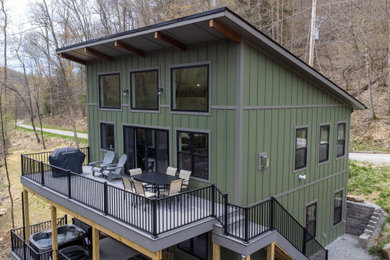 Small craftsman green two-story wood and board and batten house exterior idea in Other with a shed roof, a shingle roof and a brown roof