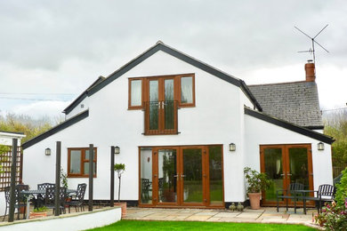 Modelo de fachada de casa blanca grande de dos plantas con revestimiento de estuco, tejado a dos aguas y tejado de teja de barro