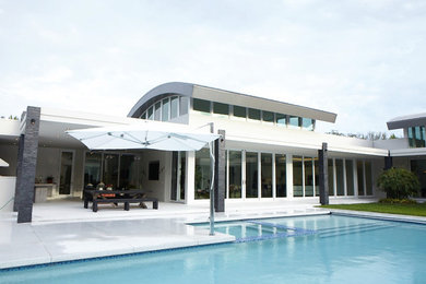 Example of a huge trendy backyard concrete and rectangular natural pool fountain design in Miami