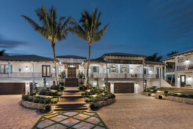 Huge island style white two-story stucco exterior home photo in Tampa with a hip roof