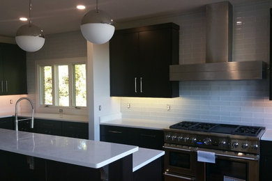 Inspiration for a large modern single-wall enclosed kitchen remodel in Other with flat-panel cabinets, dark wood cabinets, white backsplash, subway tile backsplash, stainless steel appliances, an island and white countertops