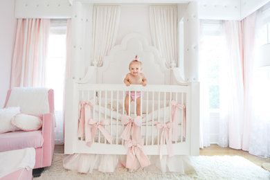 Photo of a mid-sized traditional nursery for girls in Dallas with pink walls and light hardwood floors.