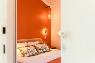 Idées déco pour une chambre parentale méditerranéenne de taille moyenne avec un mur orange, sol en stratifié et un sol marron.