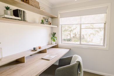 Diseño de despacho contemporáneo pequeño con paredes blancas, moqueta, escritorio empotrado y suelo marrón
