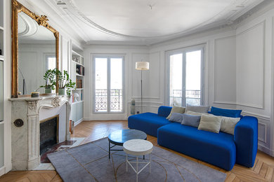 Idée de décoration pour un grand salon tradition avec un mur blanc, un sol en bois brun, une cheminée standard, un manteau de cheminée en pierre et un sol marron.