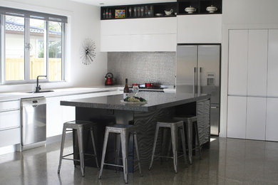 Design ideas for a mid-sized contemporary eat-in kitchen in Auckland with a single-bowl sink, white cabinets, quartz benchtops, metallic splashback, concrete floors and with island.