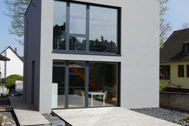 Exemple d'une façade de maison grise moderne en stuc à un étage avec un toit plat.