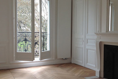 Cette photo montre un salon tendance de taille moyenne et fermé avec un mur blanc, parquet clair, une cheminée standard, un manteau de cheminée en pierre, un sol marron, une salle de réception et un téléviseur dissimulé.