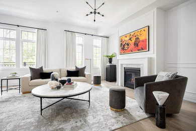 Large contemporary open plan living room in Toronto with white walls, light hardwood flooring, a standard fireplace, a wooden fireplace surround, a wall mounted tv, white floors and wainscoting.