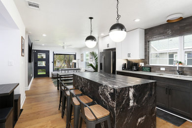 Inspiration for a mid-sized modern single-wall medium tone wood floor and brown floor eat-in kitchen remodel in Other with a drop-in sink, shaker cabinets, dark wood cabinets, granite countertops, black backsplash, ceramic backsplash, stainless steel appliances, an island and black countertops