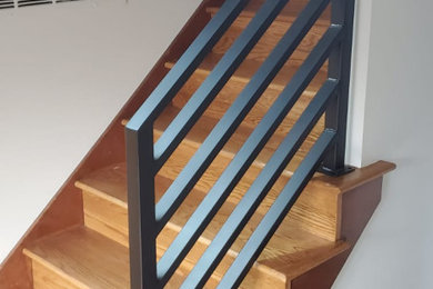 ポートランドにある高級な中くらいなミッドセンチュリースタイルのおしゃれな直階段 (木の蹴込み板、金属の手すり) の写真