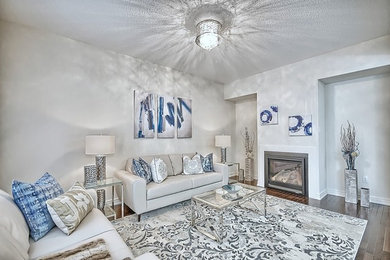 Inspiration for a mid-sized transitional open concept medium tone wood floor and brown floor family room remodel in Toronto with beige walls, a standard fireplace and a plaster fireplace