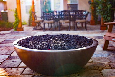 Example of a backyard stone patio design in San Luis Obispo with a fire pit and a pergola