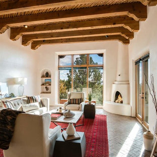 Großes, Repräsentatives, Fernseherloses, Offenes Mediterranes Wohnzimmer mit weißer Wandfarbe, Backsteinboden, Eckkamin, verputztem Kaminsims und braunem Boden in Sonstige