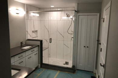 Cette photo montre une grande salle de bain moderne avec un placard à porte vitrée, des portes de placard blanches, sol en stratifié et un sol marron.
