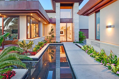 Inspiration for an expansive contemporary front door in San Diego with beige walls, granite floors, a pivot front door and a medium wood front door.