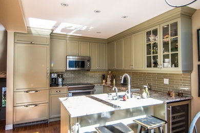 This is an example of a small transitional u-shaped eat-in kitchen in Toronto with an undermount sink, flat-panel cabinets, green cabinets, granite benchtops, green splashback, glass tile splashback, stainless steel appliances and medium hardwood floors.