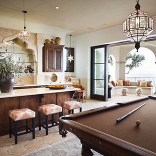 ロサンゼルスの大きい地中海スタイルのおしゃれなウェットバー (アンダーカウンターシンク、落し込みパネル扉のキャビネット、濃色木目調キャビネット、クオーツストーンカウンター、ベージュキッチンパネル、セラミックタイルのキッチンパネル、コンクリートの床、マルチカラーの床、ベージュのキッチンカウンター) の写真