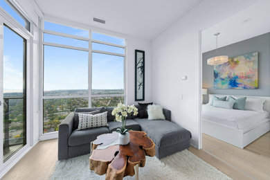 Идея дизайна: открытая, серо-белая гостиная комната среднего размера в современном стиле с светлым паркетным полом, телевизором на стене и бежевым полом